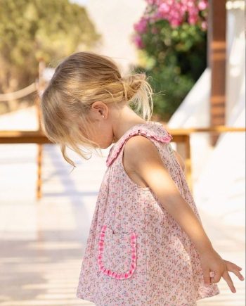 Vista lateral de vestido con bolsillos de niña, confeccionado en flores Tahití con detalles rosa fucsia