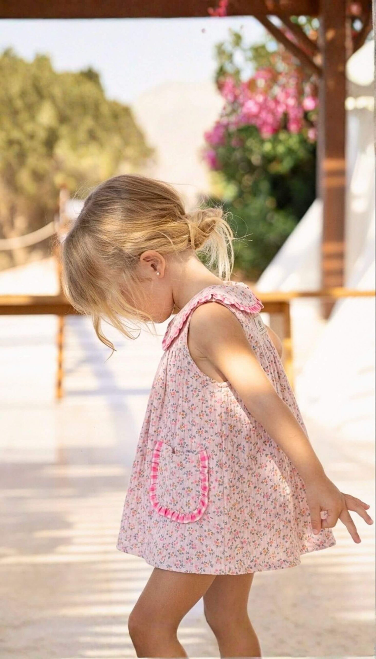 Vista lateral de vestido con bolsillos de niña, confeccionado en flores Tahití con detalles rosa fucsia