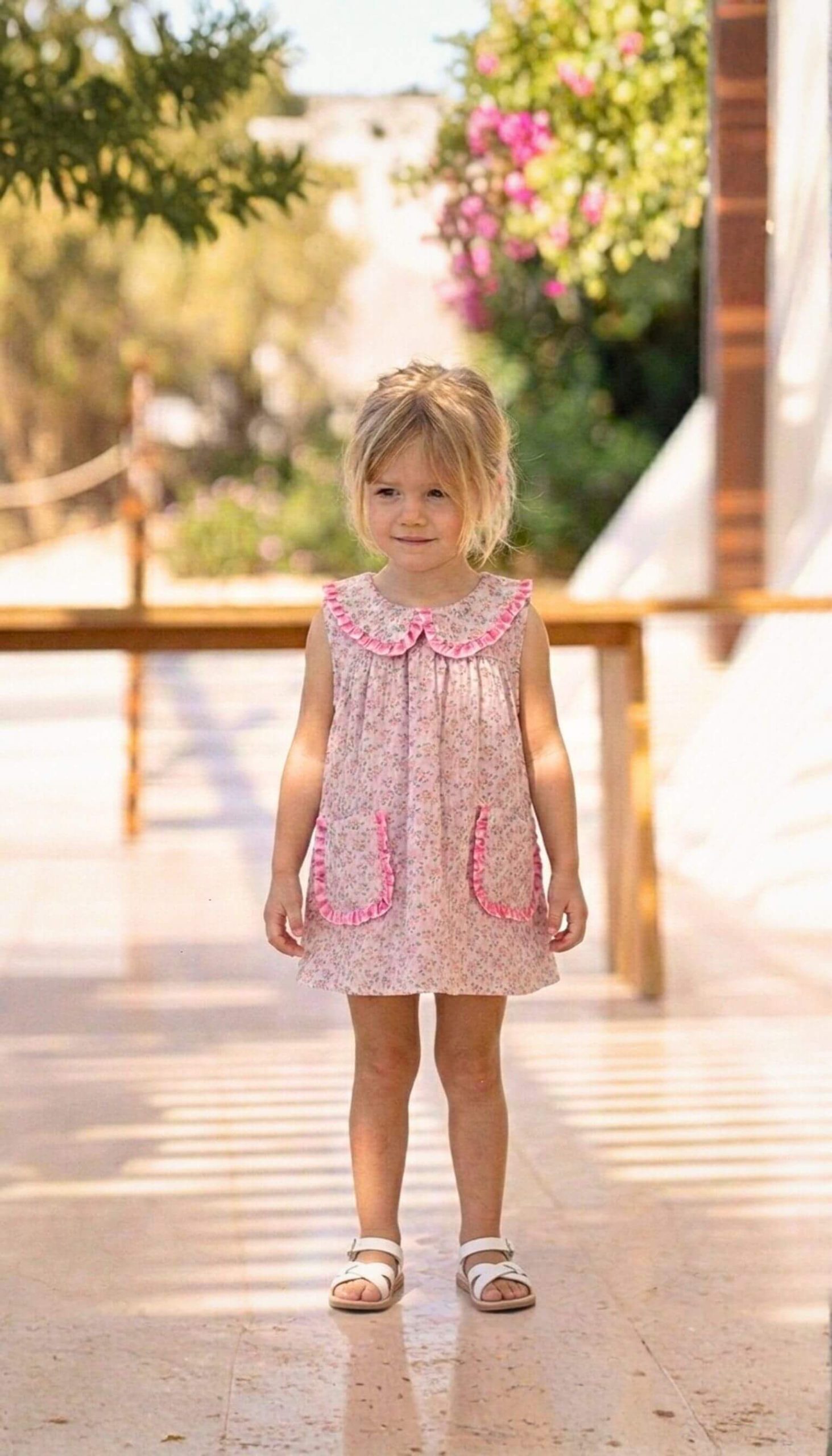 Vista delantera de vestido con bolsillos de niña, confeccionado en flores Tahiti con detalles rosa fucsia