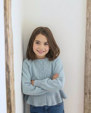 Jersey de punto azul para niña – vista lateral Jersey infantil de punto azul para niña visto de perfil.